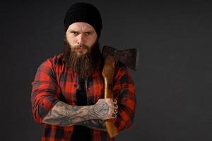 bel homme aux cheveux longs avec une hache dans les mains sur un fond de studio sombre photo