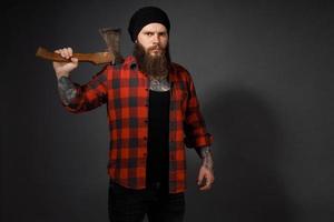 bel homme aux cheveux longs avec une hache dans les mains sur un fond de studio sombre photo