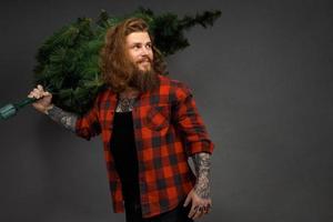 bel homme aux cheveux longs tenant un arbre de noël synthétique photo