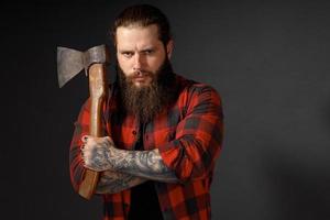 bel homme aux cheveux longs avec une hache dans les mains sur un fond de studio sombre photo