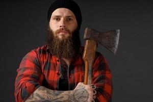 bel homme aux cheveux longs avec une hache dans les mains sur un fond de studio sombre photo