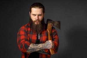 bel homme aux cheveux longs avec une hache dans les mains sur un fond de studio sombre photo