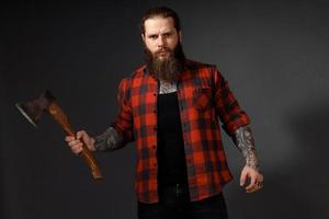 bel homme aux cheveux longs avec une hache dans les mains sur un fond de studio sombre photo