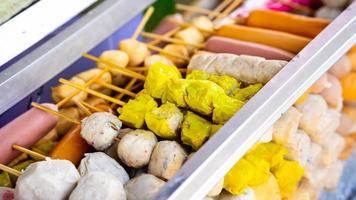 des boulettes de viande et des brochettes de saucisses assorties sont alignées dans du verre avec de la glace à vendre. l'alimentation de rue. photo