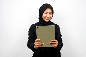 belle jeune femme musulmane asiatique souriante, excitée et joyeuse tenant une tablette, isolée sur fond blanc photo