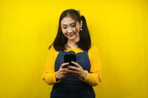 jolie et mignonne jeune femme joyeuse, confiante, avec les mains tenant un smartphone, faisant la promotion du produit, présentant quelque chose, de la publicité, isolée photo