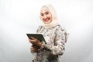 belle jeune femme musulmane asiatique souriante, excitée et joyeuse tenant une tablette, isolée sur fond blanc photo