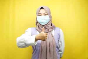 femme musulmane portant des masques médicaux, mouvement anti-virus corona, mouvement anti-covid-19, mouvement de santé utilisant des masques, avec les mains montrant le signe ok, bon travail, succès, victoire, isolé photo
