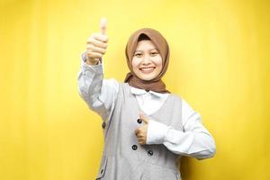 belle jeune femme musulmane asiatique souriante confiante, enthousiaste et joyeuse avec les mains en l'air, signe ok, succès, bon travail, signe de réussite, isolé sur fond jaune