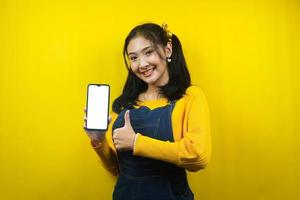 jolie et mignonne jeune femme joyeuse, confiante, mains tenant un smartphone, avec un smartphone à écran blanc ou blanc, faisant la promotion de l'application, faisant la promotion du produit, de la publicité, isolée photo