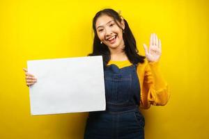 jolie et mignonne jeune femme joyeuse tenant une bannière vide vierge, une pancarte, un tableau blanc, un panneau vierge, un panneau publicitaire blanc, présentant quelque chose dans l'espace de copie, promotion photo