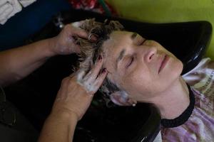 gros plan d'une cliente mature se faisant laver les cheveux par un coiffeur. photo