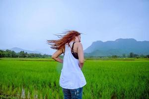 les femmes asiatiques voyagent se détendent pendant les vacances. la fille sourit heureuse et profite de la pluie qui tombe. voyager à la campagne, rizières vertes, voyager en thaïlande. photo