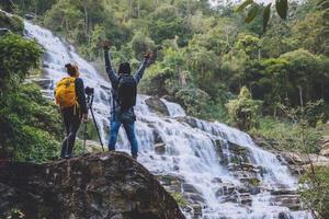 couple asiatique voyage nature. voyager se détendre. stand paysages toucher naturel stand pour voir de belles cascades mae ya à chiangmai en thaïlande