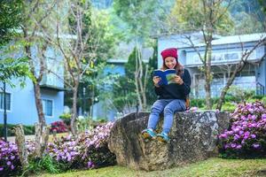 femme voyage nature dans le jardin fleuri. détendez-vous assis sur des rochers et lisez des livres au milieu de la nature à doi inthanon. photo