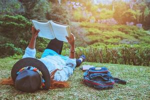 femme asiatique voyage nature. voyager se détendre. dormir en lisant un livre sur la pelouse du parc. en été. photo