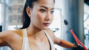 Jeune femme asiatique faisant de l'exercice en faisant de l'exercice avec un câble croisé de la machine pour brûler les graisses en cours de fitness. athlète avec six pack, activité récréative sportive, entraînement fonctionnel, mode de vie sain.