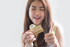 jeune femme tenant un préservatif et des pilules contraceptives empêchent la grossesse photo