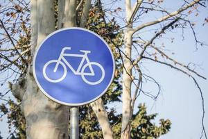 Panneau de signalisation de vélo avec des branches d'arbres en arrière-plan photo