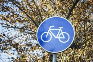 Panneau de signalisation de vélo avec des branches d'arbres en arrière-plan