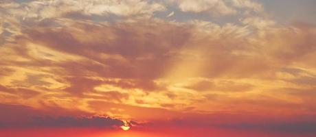 nuages orange et gris belle ambiance de coucher de soleil avec un grand soleil jaune et orange dans les collines de la surface du ciel. photo