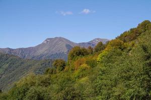 sommets des montagnes géorgiennes derrière la forêt aux couleurs de l'automne photo