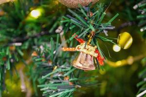 une cloche avec le mot de noël comme décoration au faux arbre photo