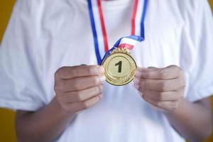 Main tenir la première place throphy sur fond jaune photo