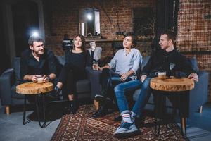 des gars et des filles joyeux sont assis sur un canapé avec des tasses dans les mains photo