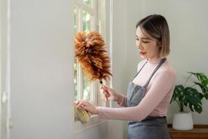 femme nettoyage fenêtre avec plume plumeau dans brillant moderne Accueil intérieur photo
