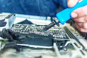 un homme répare un ordinateur, soude une carte, répare l'électronique et les technologies modernes photo