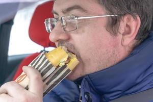 homme portant des lunettes mange un sandwich photo