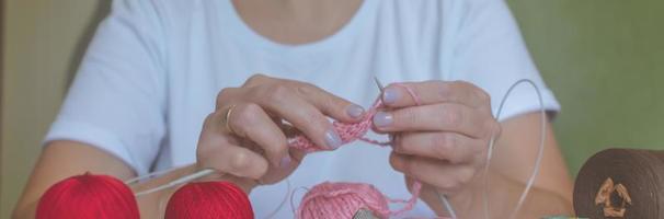 fille tricote du fil avec des aiguilles à tricoter et du crochet à la maison. dans un t-shirt blanc. tricots à la main