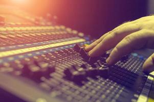 main humaine sur la console de mixage dans le studio d'enregistrement. projecteur. photo