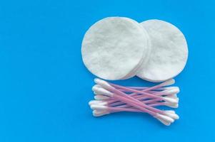 tampons de coton et bâtonnets de coton sur fond bleu avec une place pour l'écriture. le concept de soins du corps. photo