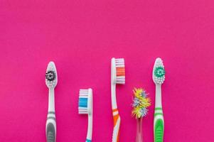 nouvelles brosses à dents multicolores et une vieille brosse à dents sur fond rose. la vue d'en haut. fermer. photo