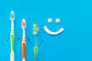 brosses à dents nouvelles et anciennes sous forme de personnages de dessins animés sur fond bleu avec un sourire dessiné avec du dentifrice. la vue depuis le sommet.le concept d'hygiène familiale. photo