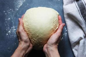 les mains de la femme tiennent une pâte serrée pour les boulettes sur la table. cuisine à la maison. mise au point sélective. photo