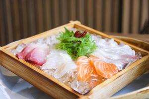 Cuisine japonaise sashimi saumon et salade de sashimi de poisson cru sur glace servi sur un plateau en bois dans le restaurant de cuisine japonaise photo