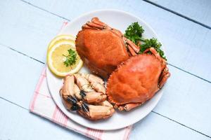 crabe cuit sur plaque blanche et fond en bois - pince de crabe en pierre rouge bouillie de fruits de mer avec des herbes et des épices photo