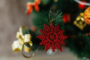 fond de vacances de noël. étoile rouge suspendue à un arbre de noël décoré avec des arcs et des boules d'or. mise au point sélective. fermer. photo