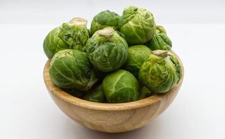 choux de Bruxelles frais dans un bol en bois isolé sur fond blanc photo