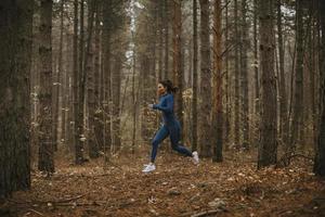 Jeune femme courant sur le sentier forestier à l'automne photo