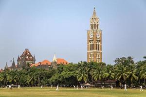 mumbai, inde, 2015 - personnes non identifiées jouant au sqiash par la tour de l'horloge de rajabai à mumbai. La tour a été achevée en 1878 et a une hauteur de 85 m. photo