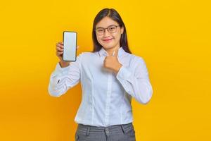 femme asiatique excitée et joyeuse montrant un écran de smartphone vierge et un pouce levé sur fond jaune