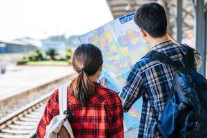 les touristes masculins et féminins regardent la carte à côté des voies ferrées. photo