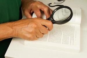 un homme tenant une loupe en regardant un livre photo