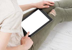 Teen woman girl using a tablet pc assis sur le sol dans un salon , touchant un écran blanc photo