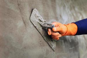 plâtrer du béton pour créer un fond de mur de travailleur industriel avec des outils de plâtrage