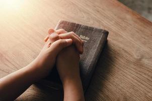 fille assise et priant pour les bénédictions de dieu avec la bible les mains jointes dans la prière biblique, spirituelle et religieuse, communiquer, parler à dieu. amour et pardon photo